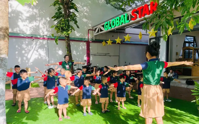 Cả lớp mầm non tập thể dục buổi sáng trên sân cỏ